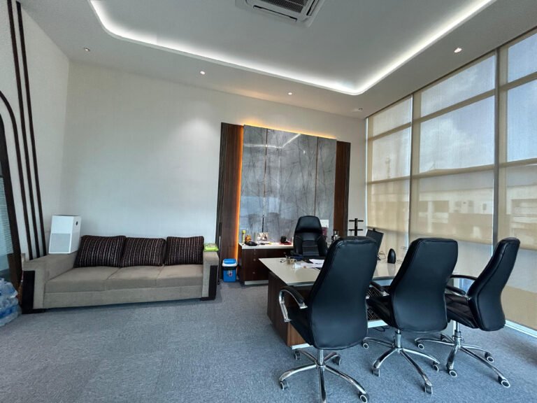 Executive corporate office interior with meeting table, seating, and ambient lighting.